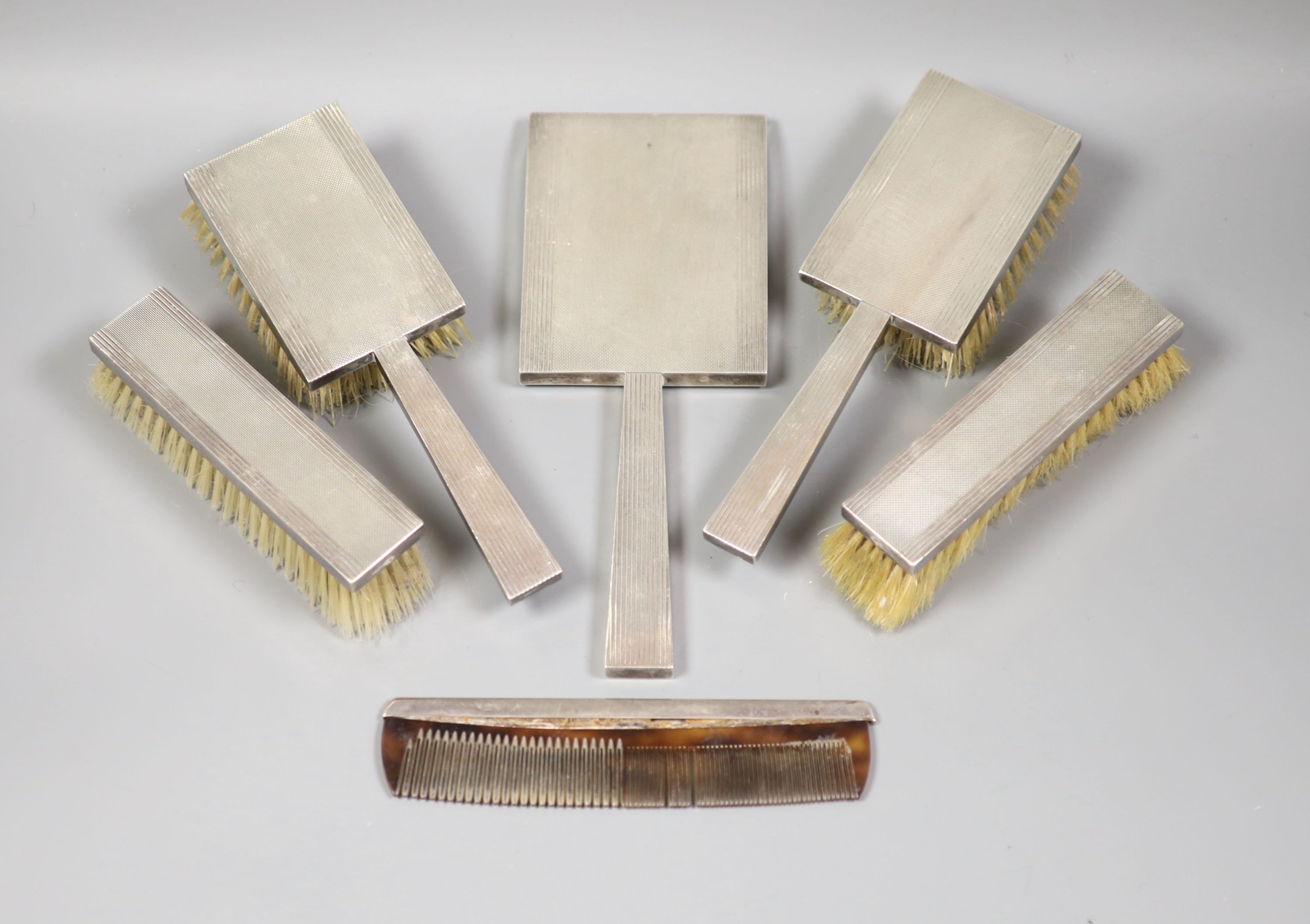 A George VI engine turned silver mounted Art Deco five piece mirror and brush set, S.J. Rose & Son, London, 1947 and an associated silver mounted comb.